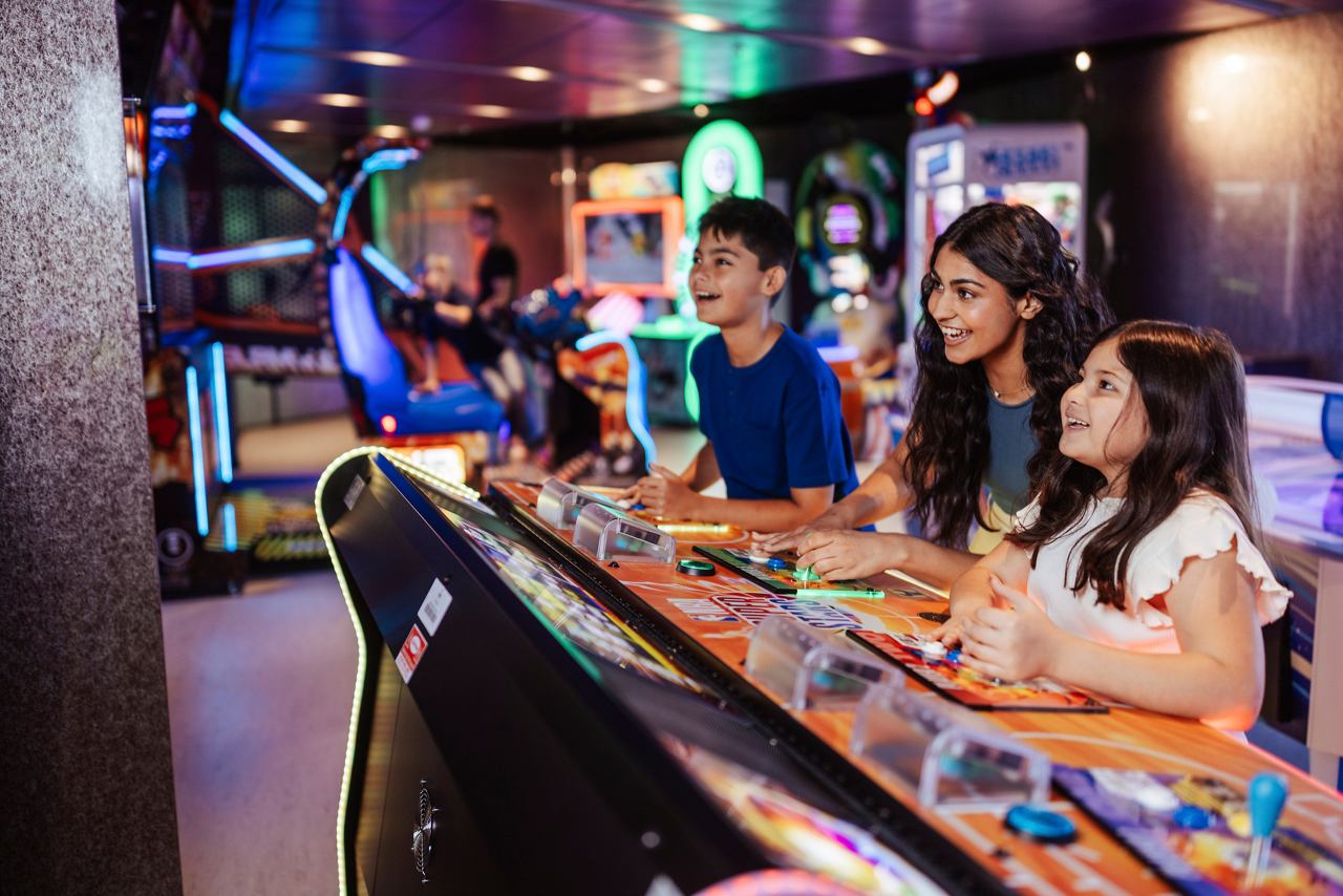 Eine Familie genießt interaktive Spiele gemeinsam in der Spielhalle auf der MSC World America | MSC Cruises