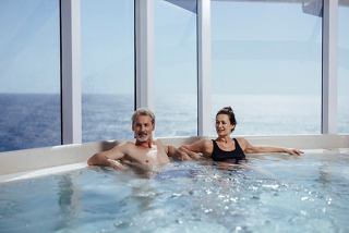 A couple relaxes together in a whirlpool bath with ocean views, enjoying their time on board MSC World America | MSC Cruises