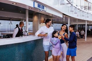 Una familia disfrutando de refrescos juntos en el bar de la cubierta del MSC World America | MSC Cruceros