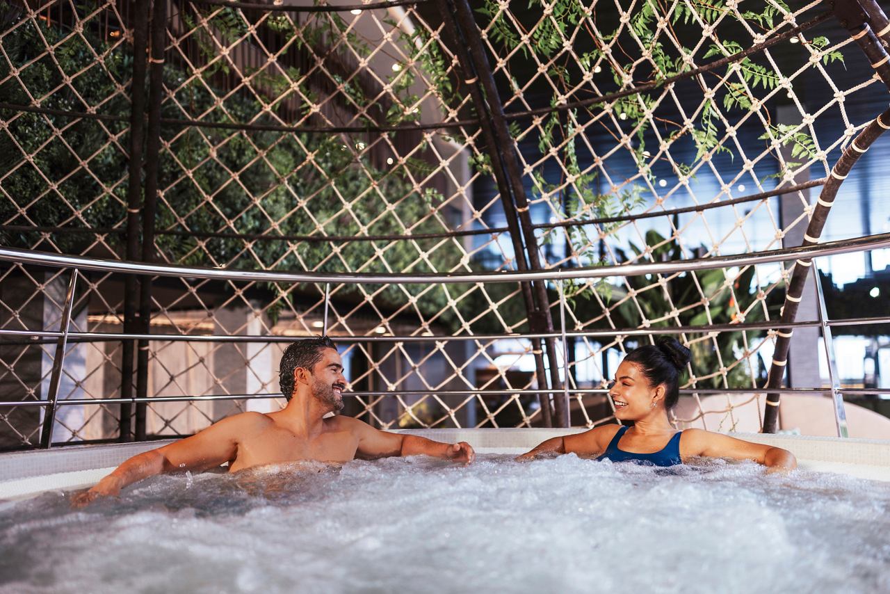 Ein Paar genießt gemeinsam Entspannung in einem Whirlpool, umgeben von üppigem Grün auf dem Deck | MSC Cruises