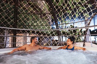 Ein Paar genießt gemeinsam Entspannung in einem Whirlpool, umgeben von üppigem Grün auf dem Deck | MSC Cruises
