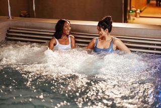 Two friends enjoy relaxation in a whirlpool bath, surrounded by soothing water and warm atmosphere | MSC Cruises