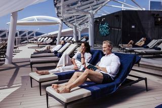 A couple enjoying cocktails while relaxing on sunbeds at the MSC Yacht Club Sundeck | MSC Cruises