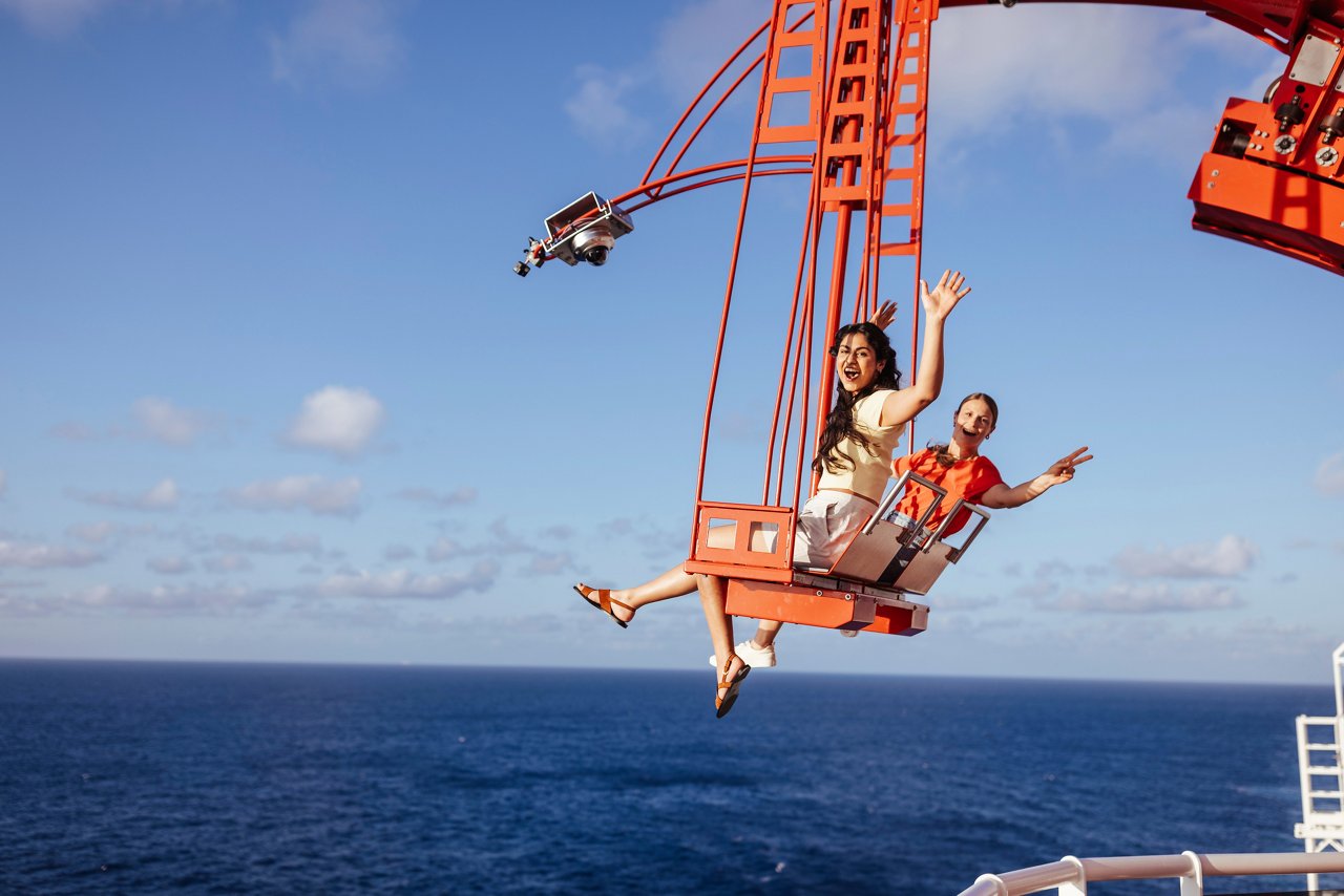 A group of friends joyfully enjoying The Cliffhanger experience above the sea under a bright sky | MSC Cruises