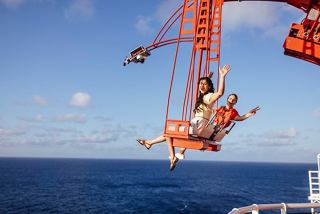 Un gruppo di amici si diverte gioiosamente nell'esperienza The Cliffhanger sopra il mare sotto un cielo sereno | MSC Crociere
