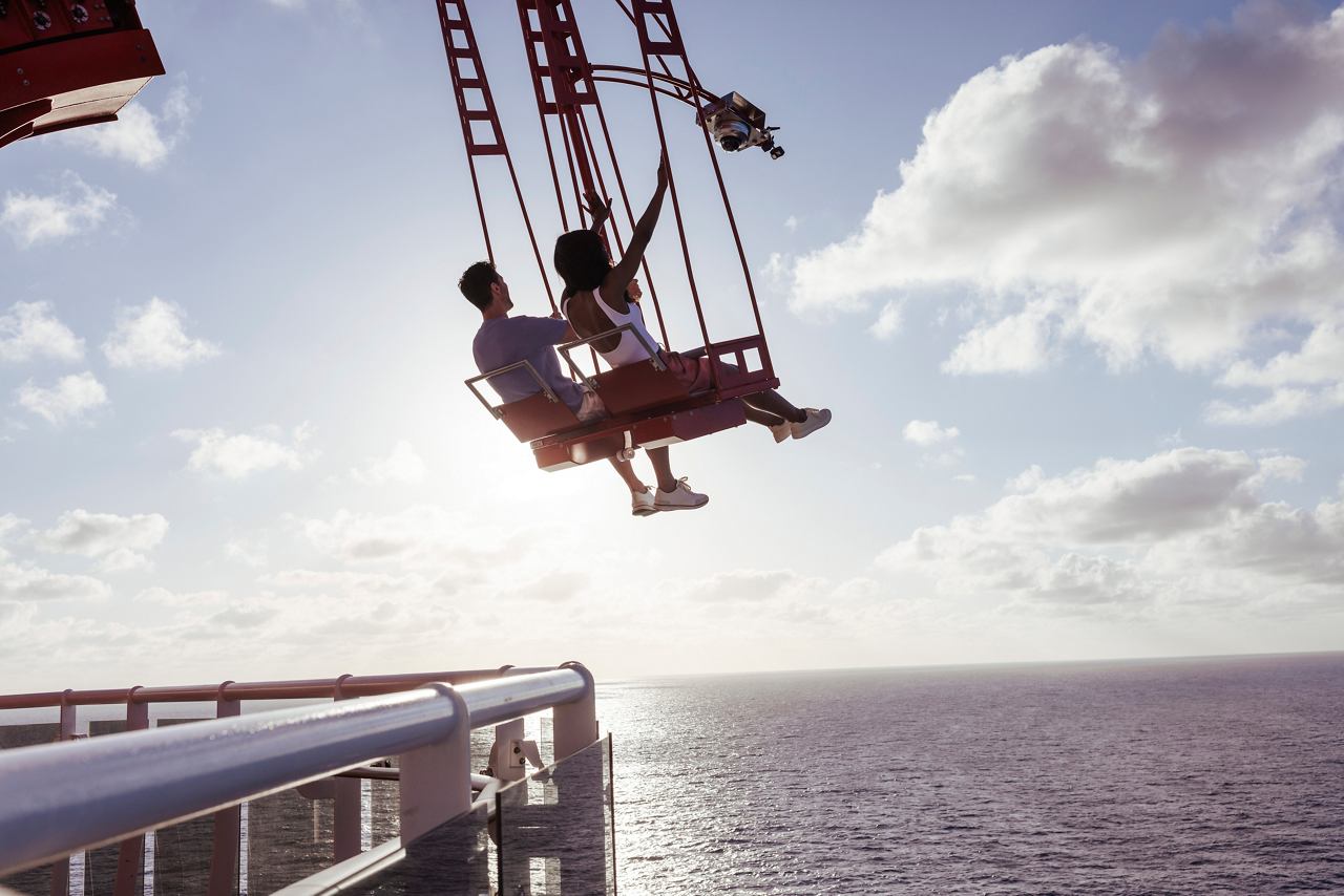 Ein Paar genießt eine aufregende Schwingfahrt über dem Ozean, umgeben von einem schönen Himmel und lebhaften Meerblicken | MSC Cruises
