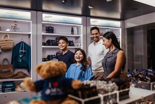 Eine Familie genießt das gemeinsame Einkaufen mit einem Teddybär im MSC World America Shop | MSC Cruises