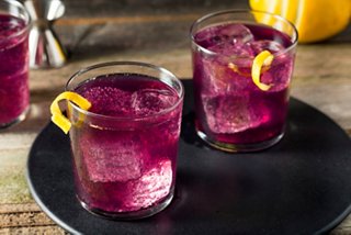 Two purple cocktails garnished with lemon zest on a black tray | MSC Cruises