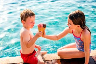Children joyfully sharing ice cream by the pool, creating lasting memories together | MSC Cruises