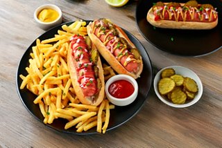 Plate featuring hot dogs and fries, served with ketchup and pickles | MSC Cruises