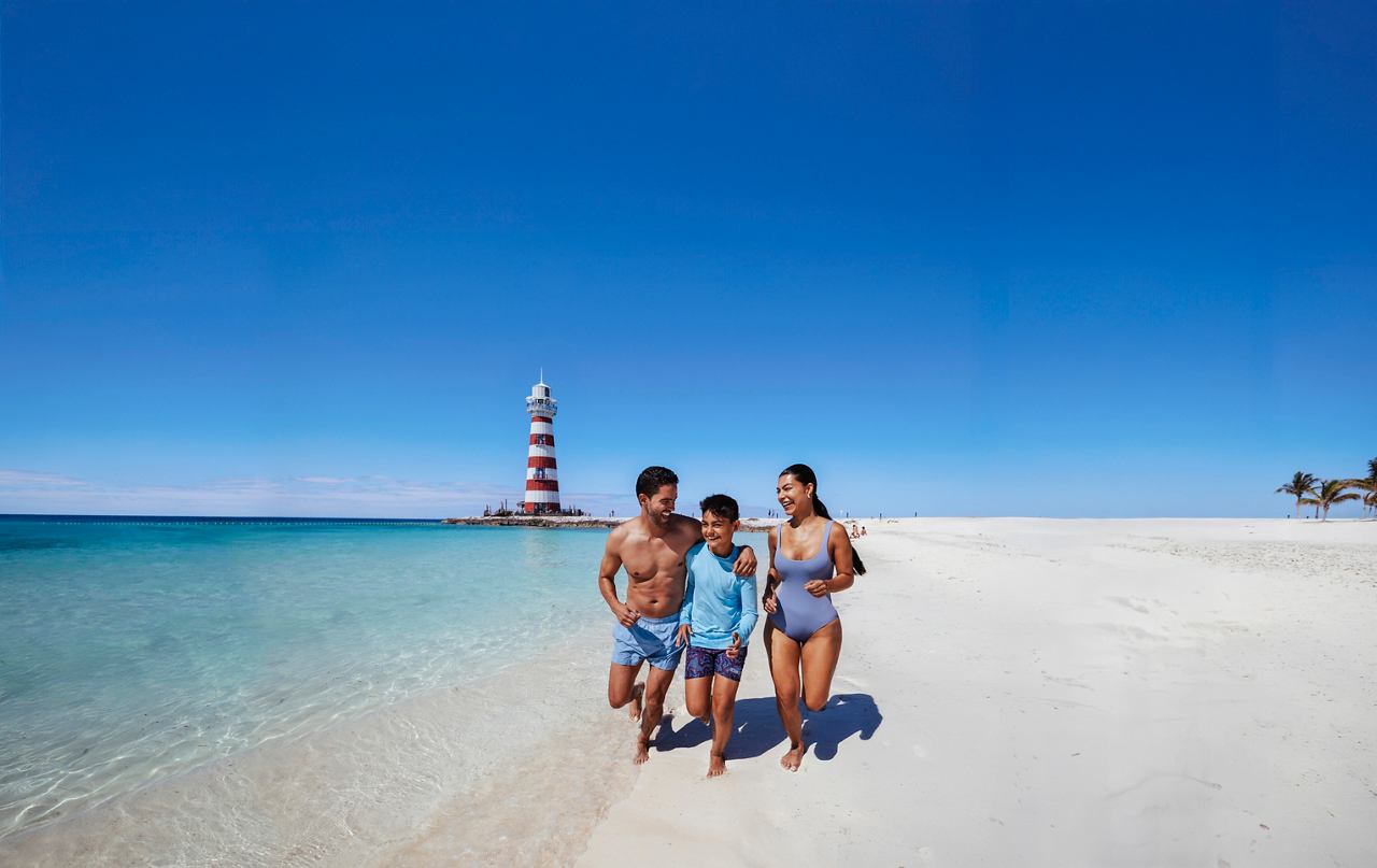 Una familia disfruta de un día soleado en la playa con aguas claras y un cielo azul | MSC Cruceros