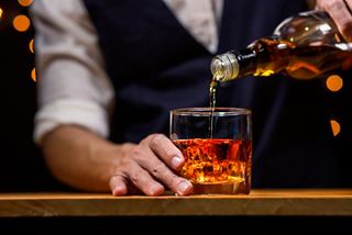 A barman pours whiskey into a glass at the bar counter of The Savannah Bar on MSC Orchestra | MSC Cruises