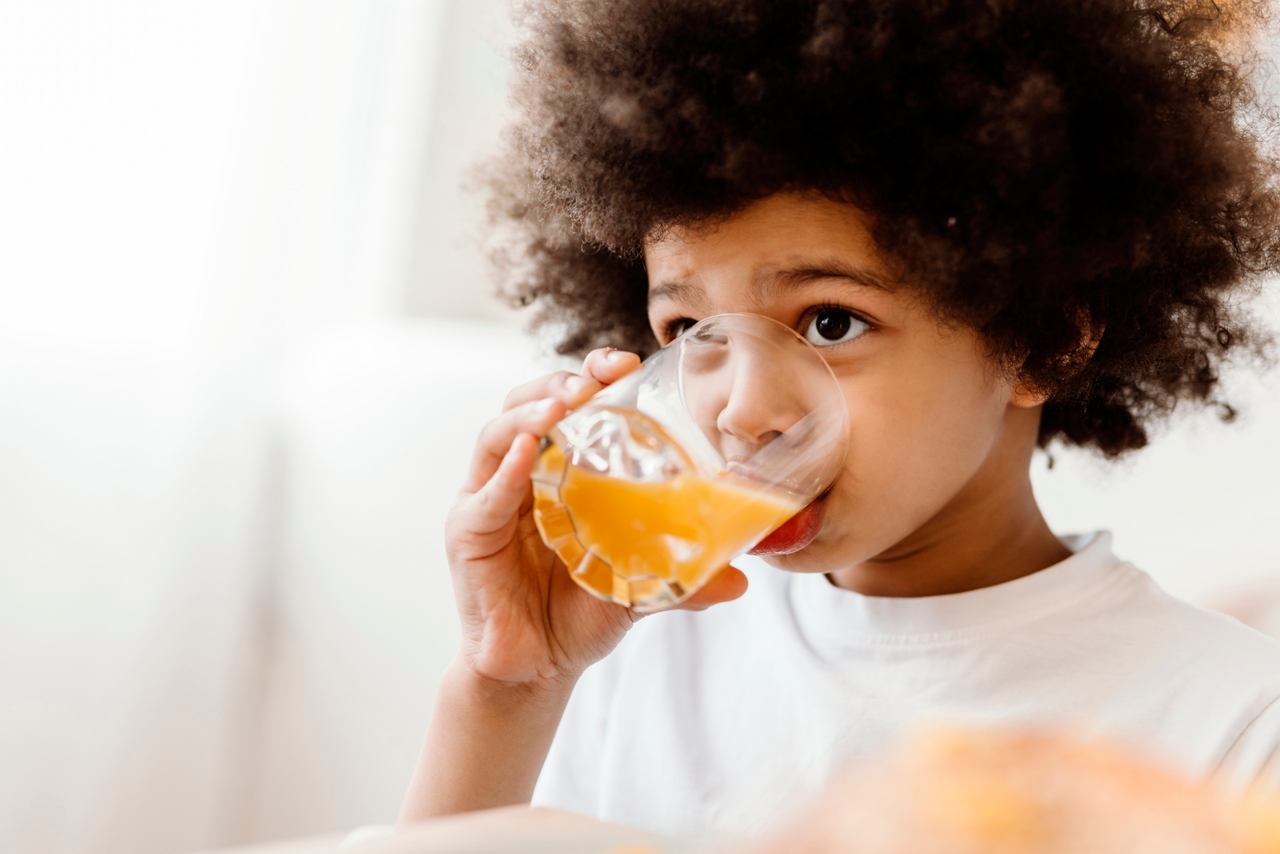 Un niño pequeño disfruta de un refrescante vaso de jugo mientras está cómodamente sentado en The Vitamin Bar | MSC Cruises