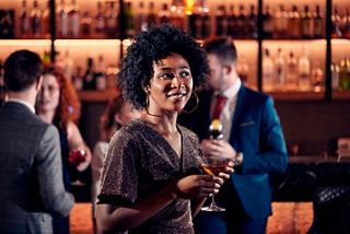 A woman smiles holding a cocktail while enjoying time with friends at a bar | MSC Cruises