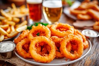 A plate of crispy onion rings served with beer and fries, perfect for sharing in the Sport Bar on MSC Splendida | MSC Cruises
