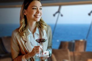 A woman enjoys a glass of red wine while admiring the ocean view from the Sky Lounge aboard MSC Euribia | MSC Cruises