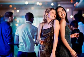 Two friends enjoying drinks at a lively bar with a vibrant atmosphere on board MSC Meraviglia | MSC Cruises