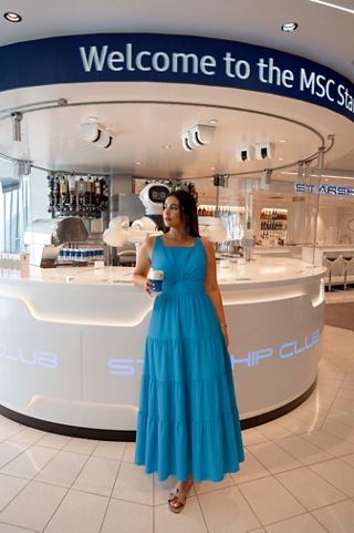 Woman in a blue dress stands by the bar counter on MSC Virtuosa | MSC Cruises