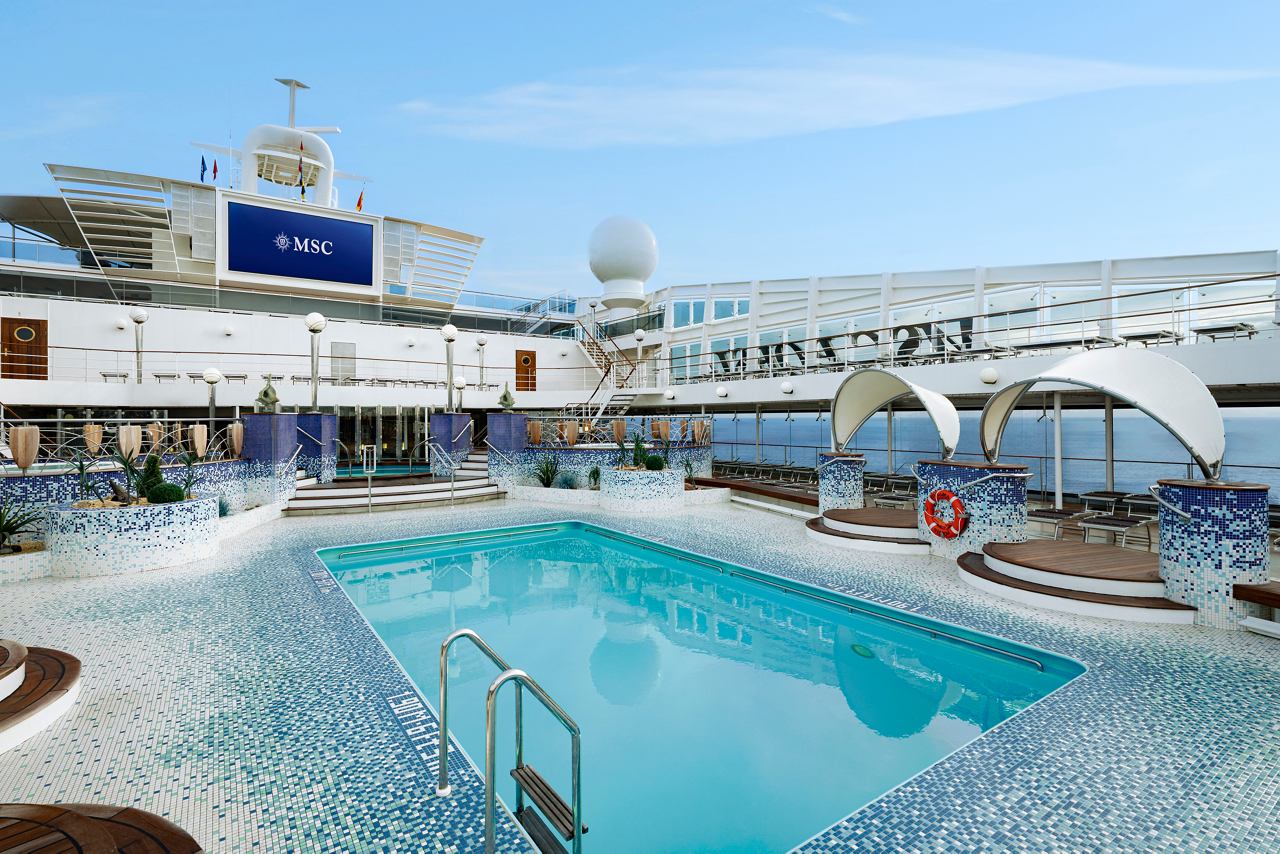Relax by the sparkling pool with sunbeds and a beautiful sea view on the deck of MSC Poesia | MSC Cruises