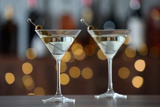 Two elegant martini glasses with olives, set against a softly lit background, inviting you to enjoy a refreshing cocktail experience | MSC Cruises