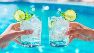 Two hands raise refreshing cocktails with lime slices, set against a vibrant pool backdrop | MSC Cruises