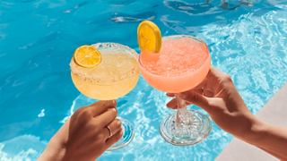 Two hands clinking cocktails by a poolside, celebrating vibrant flavours and relaxation | MSC Cruises