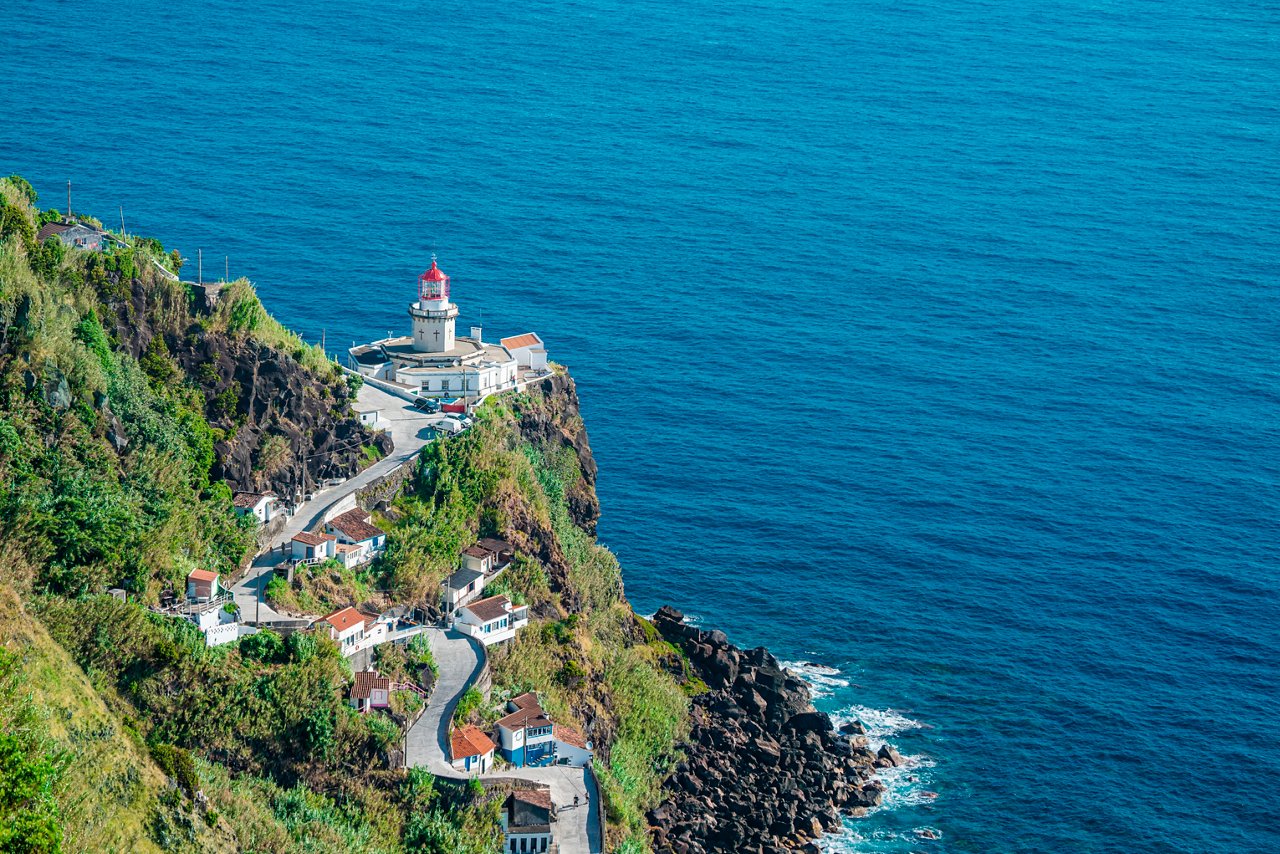 A scenic view of a lighthouse on a cliff overlooking the deep blue sea in Ponta do Arnel, São Miguel, Portugal | MSC Cruises