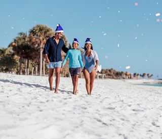Family in hats walking on a white sand beach under a clear blue sky | MSC Cruises