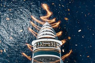 Aerial view of MSC World Europa with festive lights illuminating the ship's prow | MSC Cruises