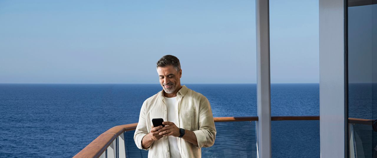 Man on balcony with phone, enjoying the serene sea view | MSC Cruises