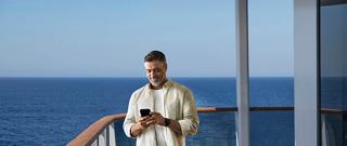 Man on balcony with phone, enjoying the serene sea view | MSC Cruises