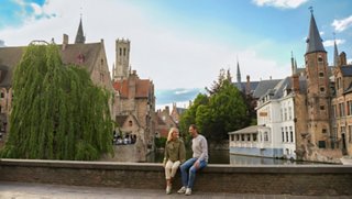 A couple enjoys the stunning architecture and canal in Bruges, Belgium | MSC Cruises