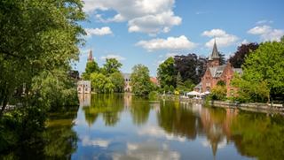Serene view of the canal with reflections and greenery in Bruges, Belgium | MSC Cruises