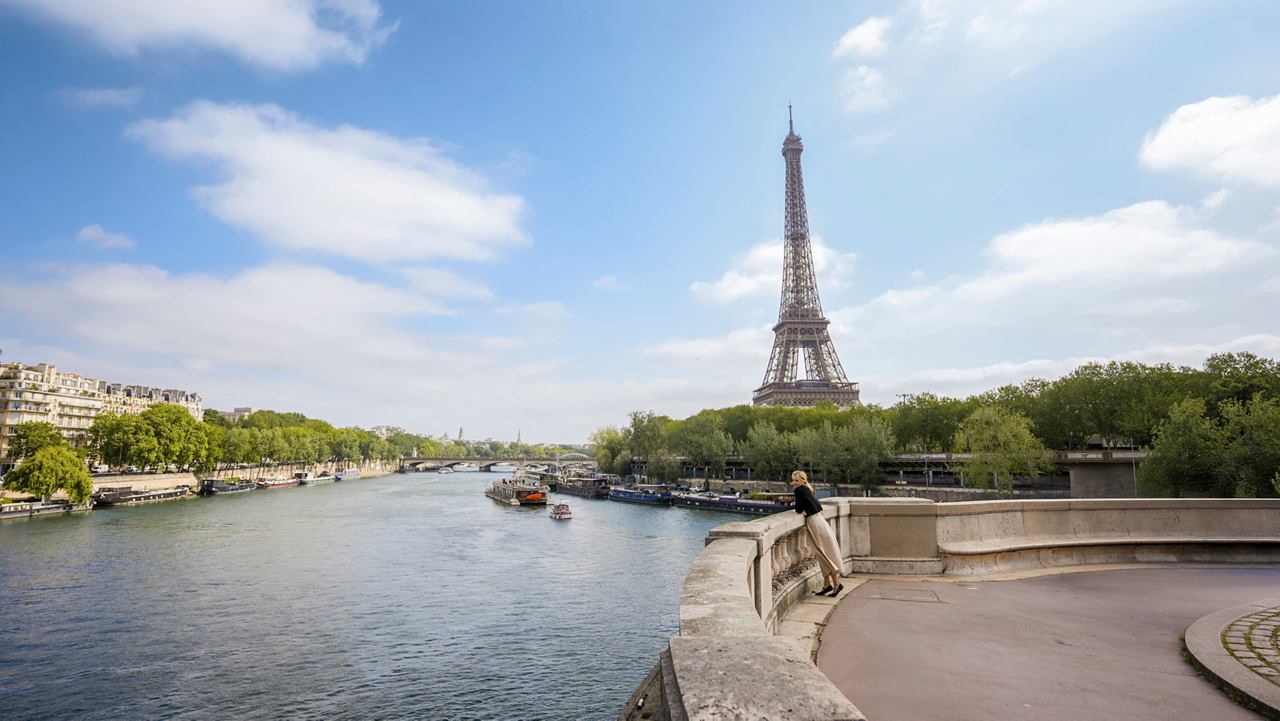 Der Eiffelturm erhebt sich über die Seine, umgeben von Grün und blauem Himmel | MSC Cruises
