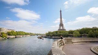 Der Eiffelturm erhebt sich über die Seine, umgeben von Grün und blauem Himmel | MSC Cruises