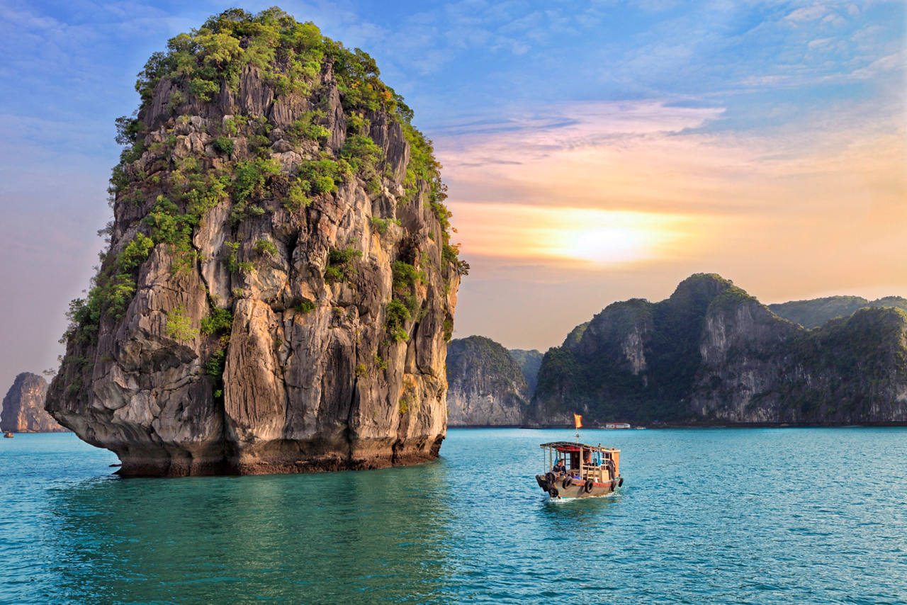 Calm sea with a boat by a stunning rock in Ha Long Bay, Vietnam | MSC Cruises