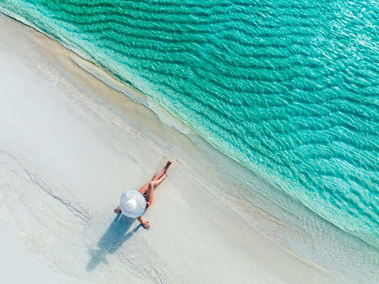 Une femme avec un parasol sur la plage profite de la tranquillité des Caraïbes | MSC Croisières