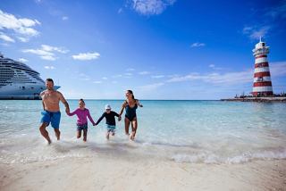 A family enjoys a sunny day at the beach with a lighthouse in the background | MSC Cruises