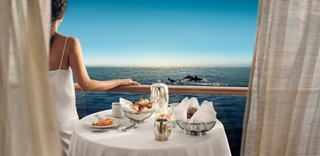 Mujer disfruta de un desayuno en el balcón con vista al mar | MSC Cruceros