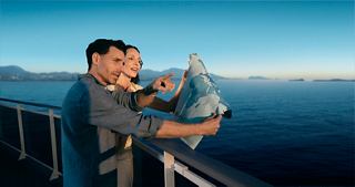 A couple gazes at the sea, pointing towards their travel destination | MSC Cruises