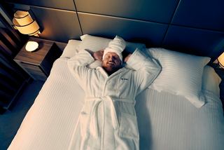 Mann im Bademantel liegt bequem im Bett mit Licht im Raum | MSC Cruises