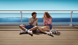 Jeunes amis profitent de la vue sur la mer sur le pont avec une pizza à la main | MSC Croisières