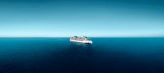 A ship sails across the open sea under a clear blue sky | MSC Cruises