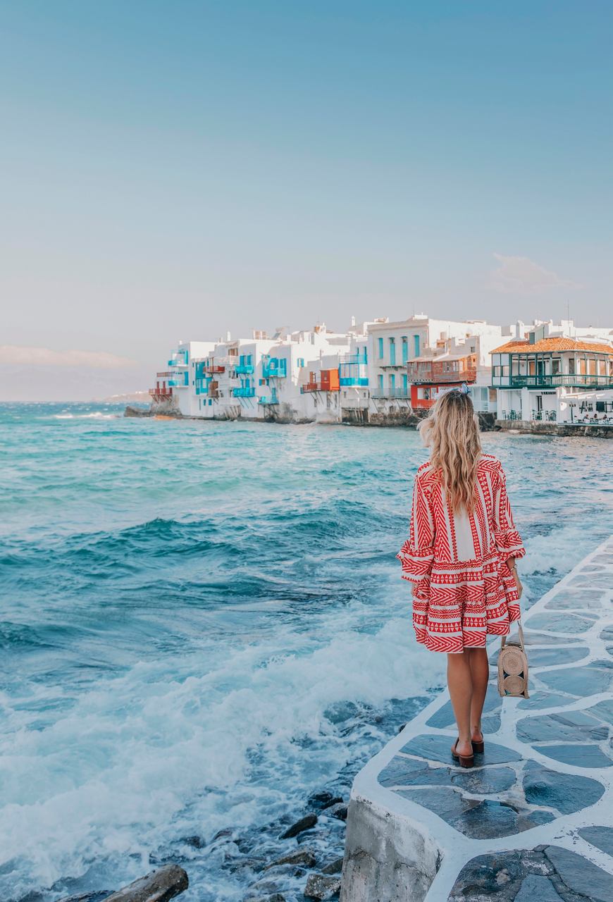 Donna sulla spiaggia a Mykonos, Grecia, con mare blu e cielo sereno sullo sfondo | MSC Crociere