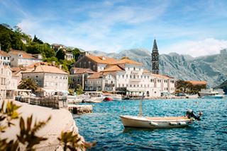 Hermosa vista de la bahía de Kotor con casas y un barco contra el fondo del cielo y las montañas | MSC Cruceros