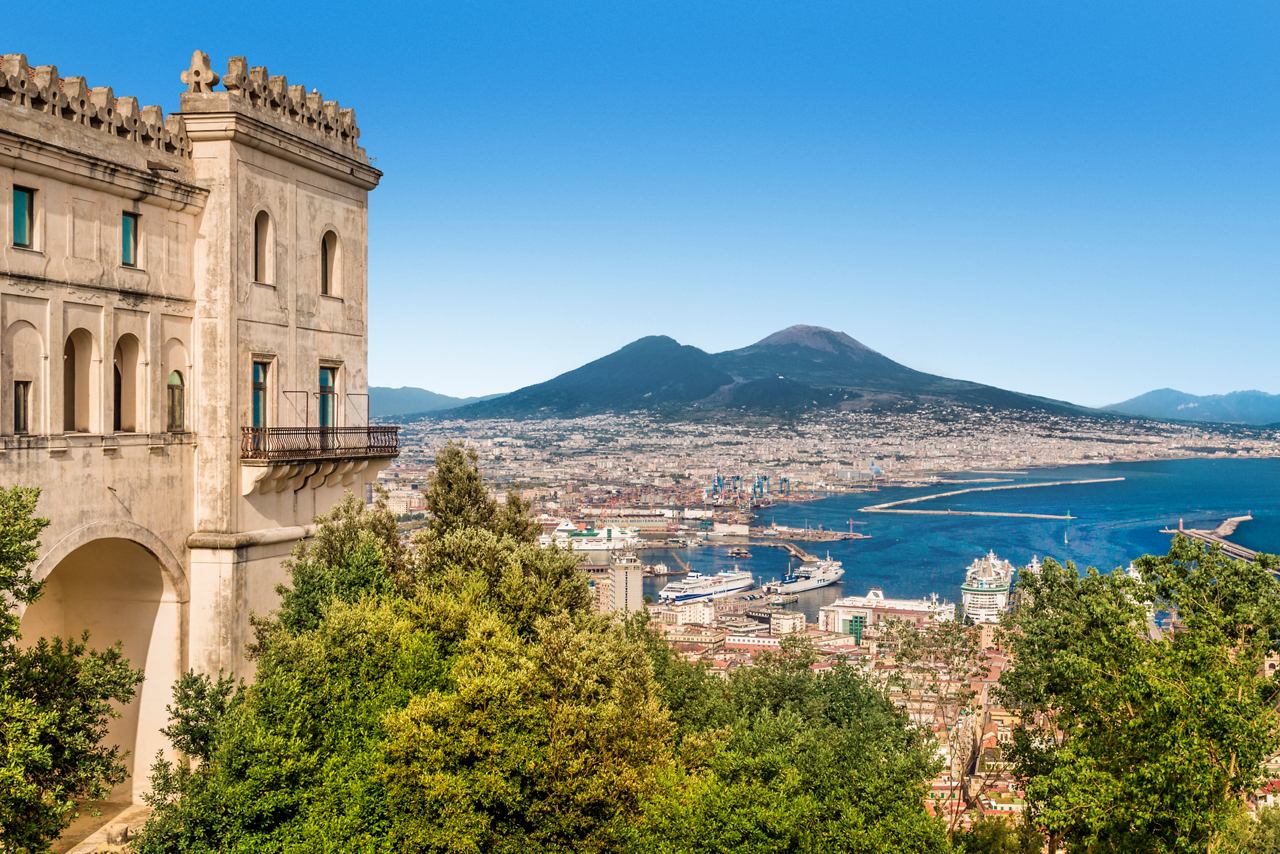 View of Mount Vesuvius and the Bay of Naples with a historic building in the foreground | MSC Cruises