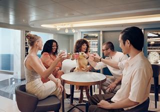 A group of friends toasting with drinks in a cocktail bar, enjoying each other's company | MSC Cruises