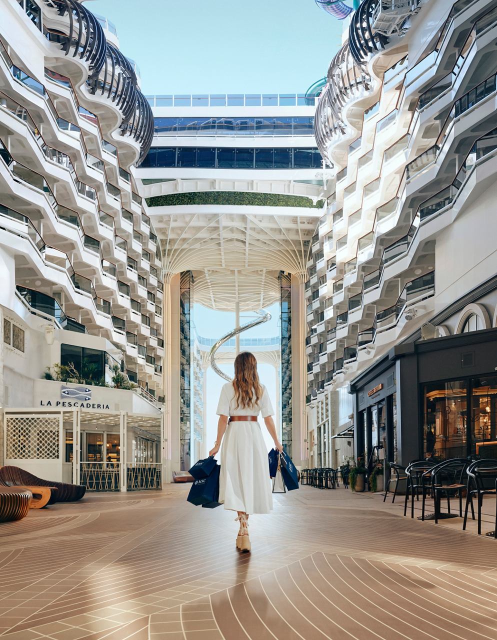 Frau in einem weißen Kleid steht im geräumigen Innenbereich der MSC World Europa | MSC Cruises