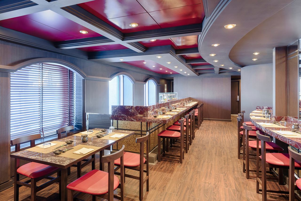 Modernes Restaurant mit Tischen und Stühlen, beleuchtet von großen Fenstern | MSC Cruises