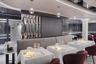 Área de comedor moderna en el MSC Yacht Club con mesas elegantes y asientos cómodos | MSC Cruceros
